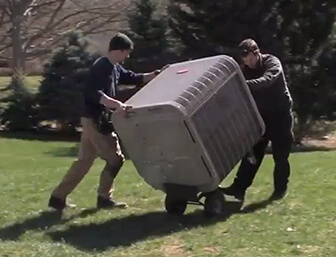 Two technicians moving a heating unit.