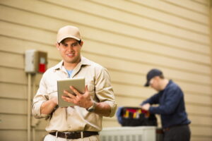 Two technicians servicing a heat pump outside of a home.